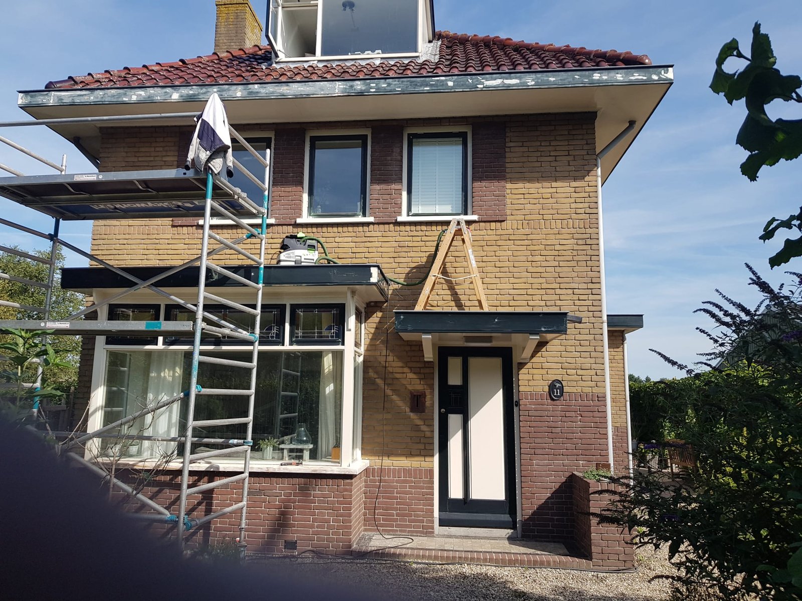 Steiger langs een woonhuis tijdens schilderwerk