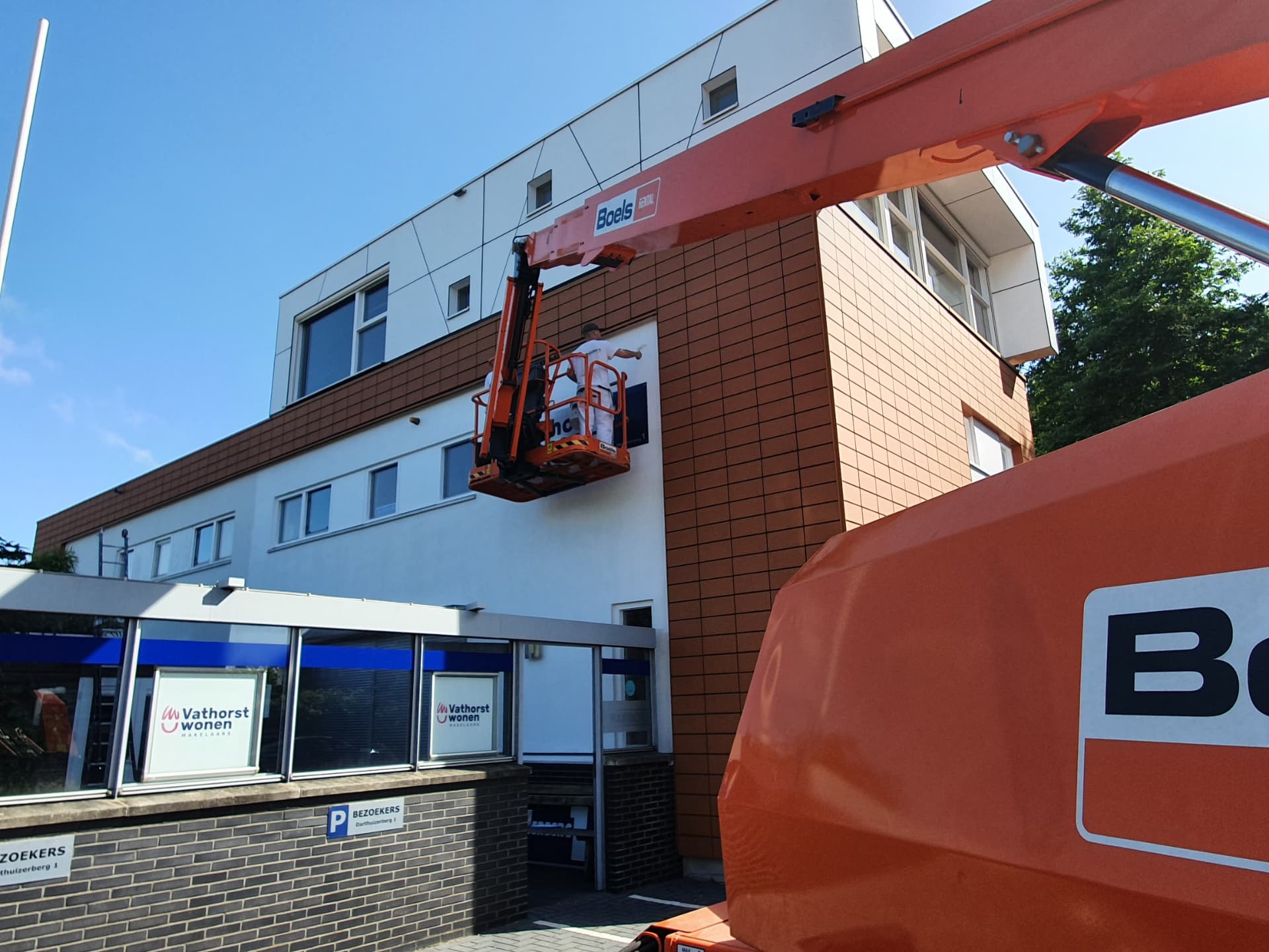 Schilder van MG Schilders in een hoogwerker bij een kantoorpand